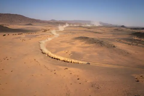 Valery HACHE / AFP A car follows a dusty track in the Saudi desert, as it takes part in the Dakar Rally.