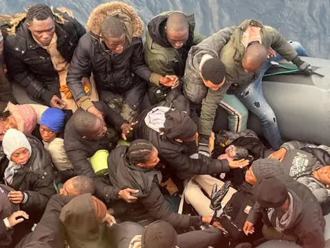 Salvamento Maritimo/Handout via Reuters A migrant holds a newborn baby as a woman lies in a rubber boat with other migrants who were rescued from the Canary Islands.