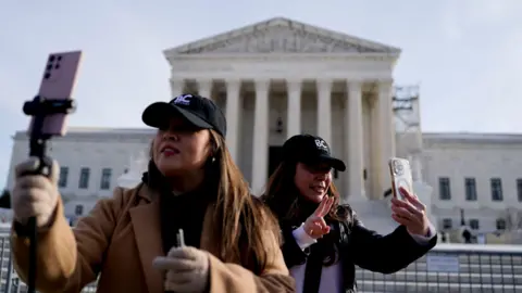 Getty Images Two women hold phones outside the Supreme Court in Washington DC.