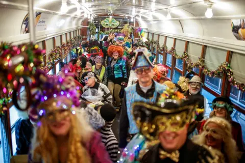 Eduardo Munoz / REUTERS Revelers wearing fancy dress, masks and wigs inside a streetcar as part of a parade in New Orleans